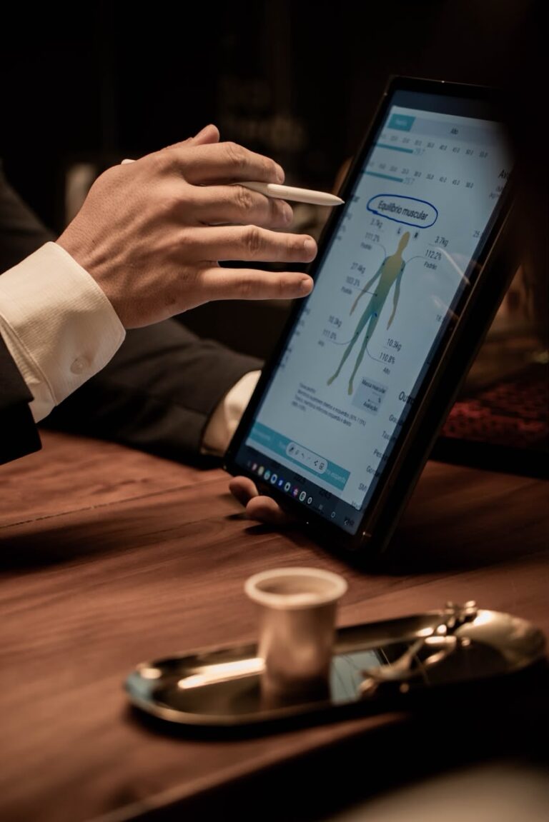 Mão do Dr. Eliphas Levi com caneta digital apontando o gráfico de equilíbrio muscular de um laudo exibido em tablet